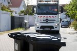 Müllauto fährt auf Mülltonnen zu