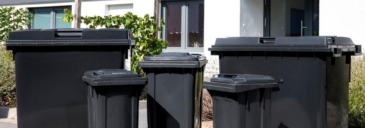 Diverse schwarze Mülltonnen und Container der AVR Kommunal