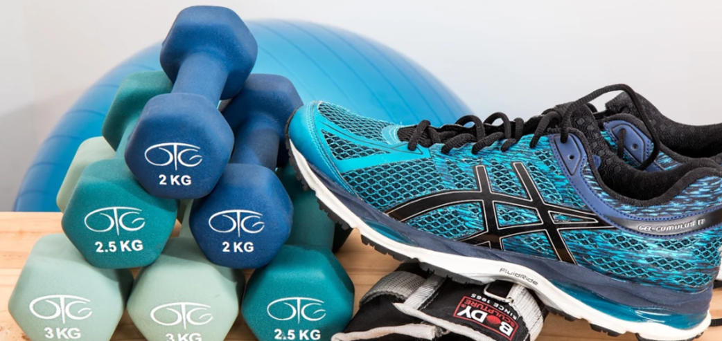 Turnschuhe, Hanteln und ein Gymnastikball