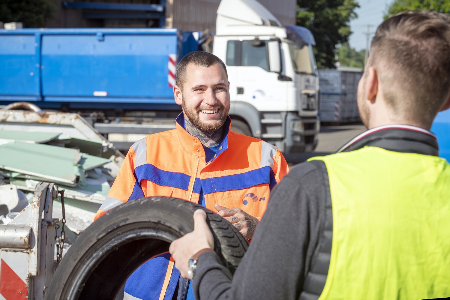 Mitarbeiter der AVR Kommunal übergeben einander einen Autoreifen