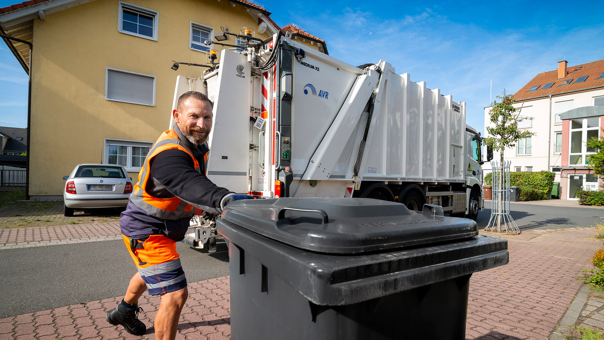 Ein Mitarbeiter der AVR Kommunal bei der Abholung einer schwarzen Mülltonne