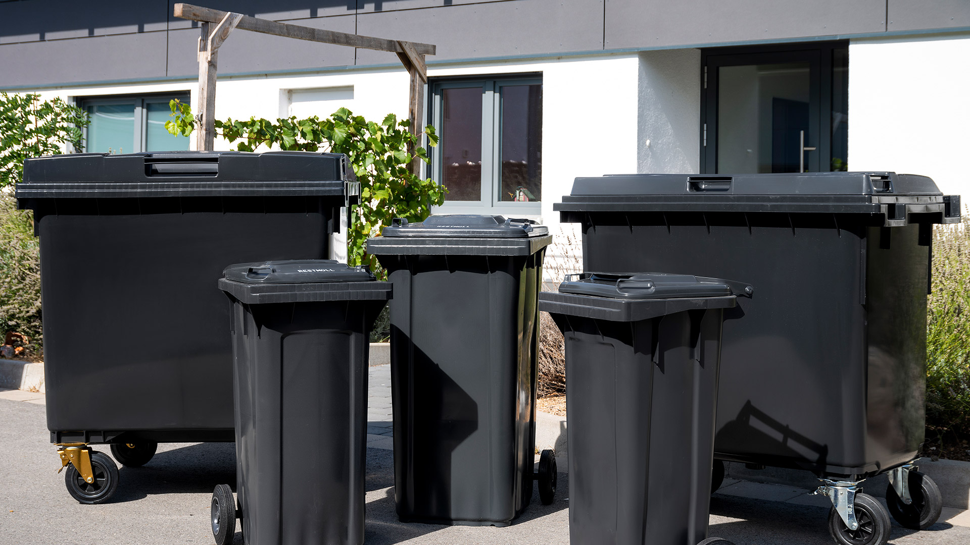 Diverse schwarze Mülltonnen und Container der AVR Kommunal