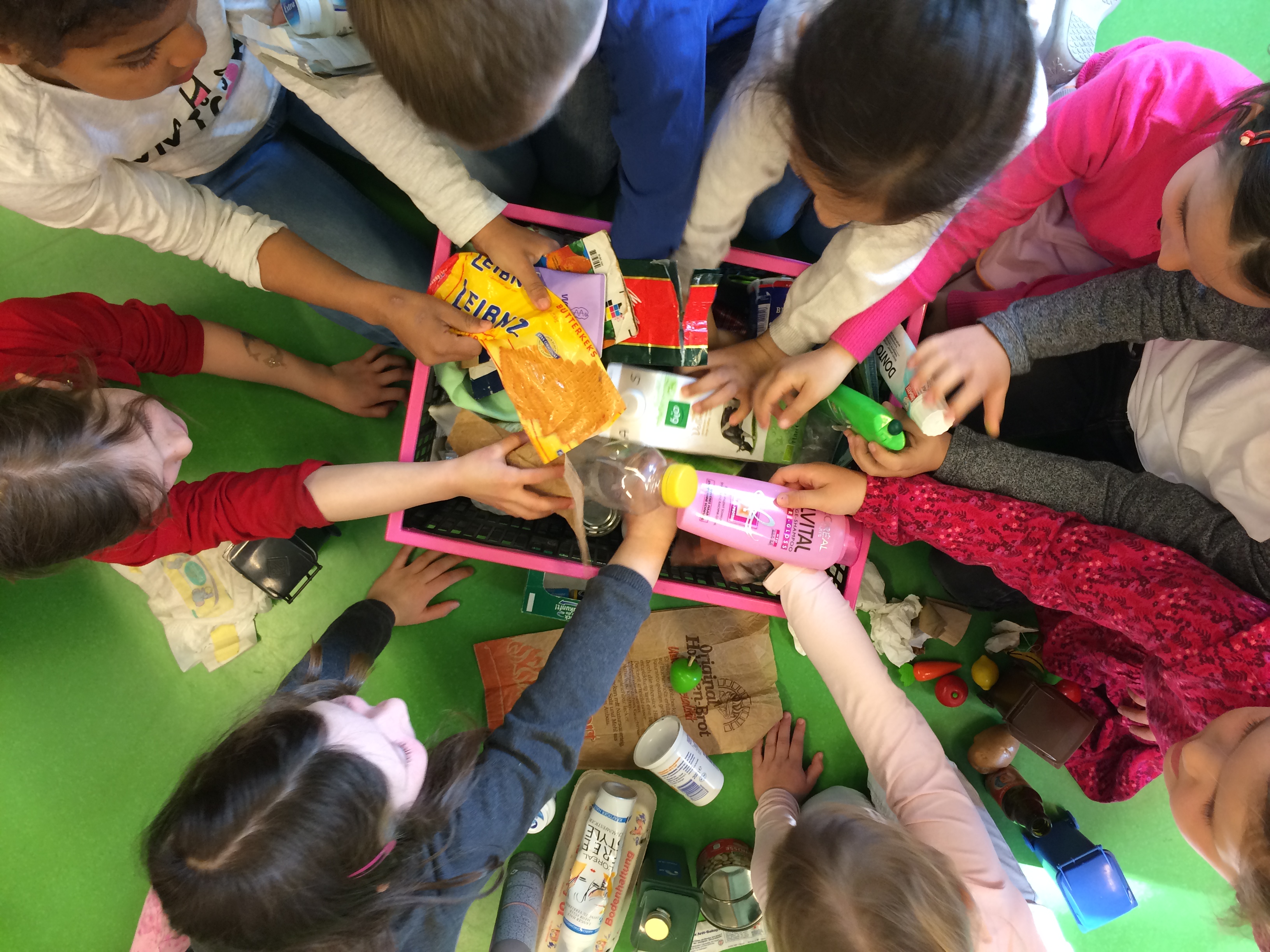 Kinder, die sich um eine Kiste mit Plastikabfall scharen